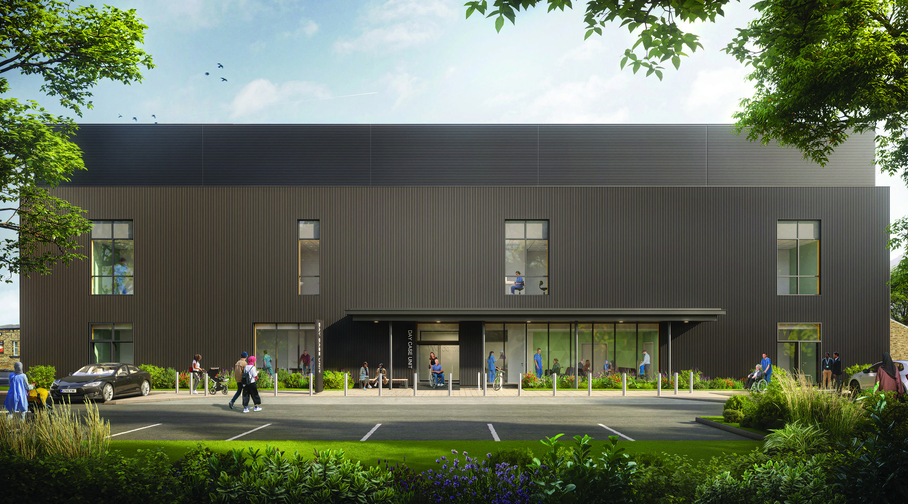 Architectural render of the external design of the new day case unit. The building is finished with ribbed, dark grey cladding and there are large windows on both floors. The main entrance features a large glass area and a wide canopy. A number of people can be seen inside and outside the building.