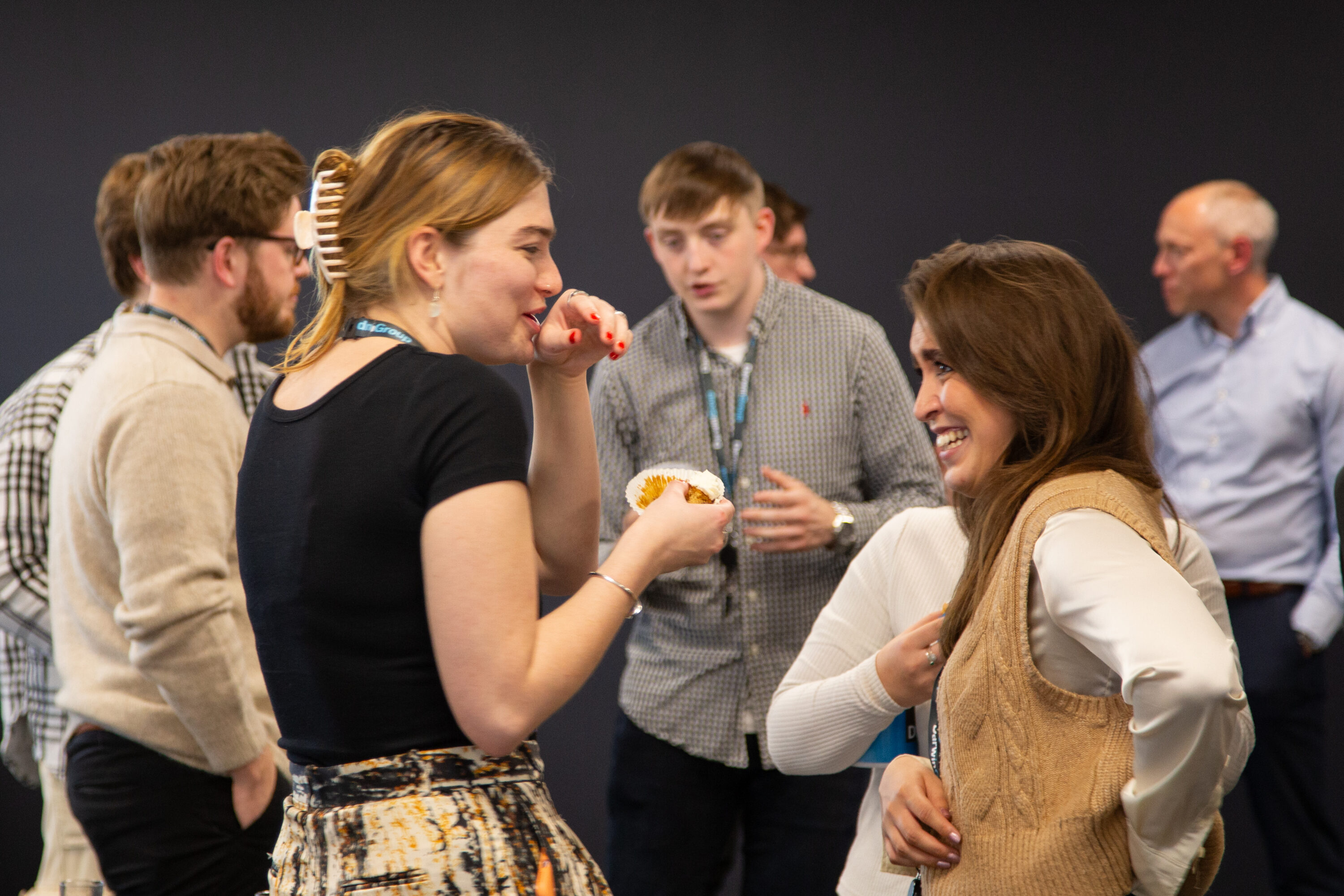 Some Darwin Group staff members enjoying a conversation in the staff hub. They are laughing and one of them is eating cake.
