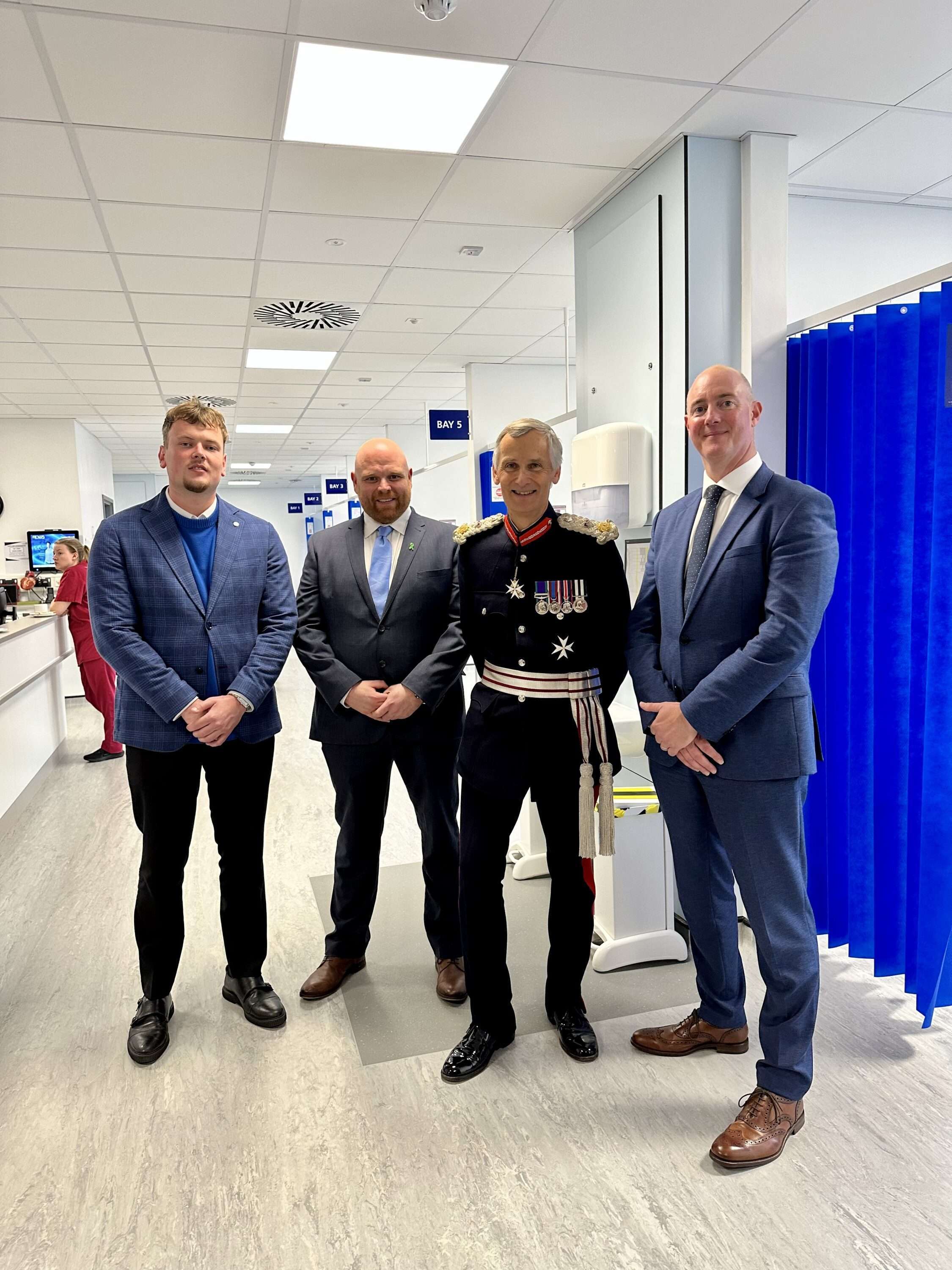 Four men, including one in ceremonial uniform, stood in a newly completed hospital building.