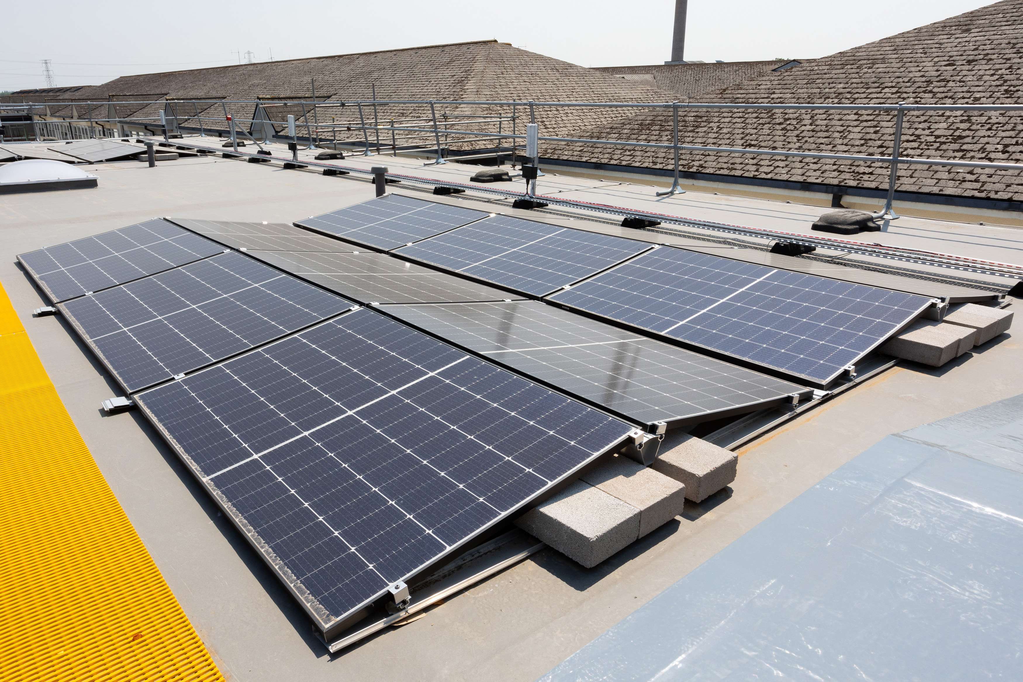 A set of photovoltaic solar panels on the roof of a hospital building.